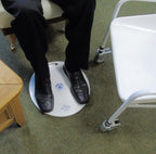 Person wearing black shoes stepping on a round white medidisk platform with a logo on a green carpeted floor.