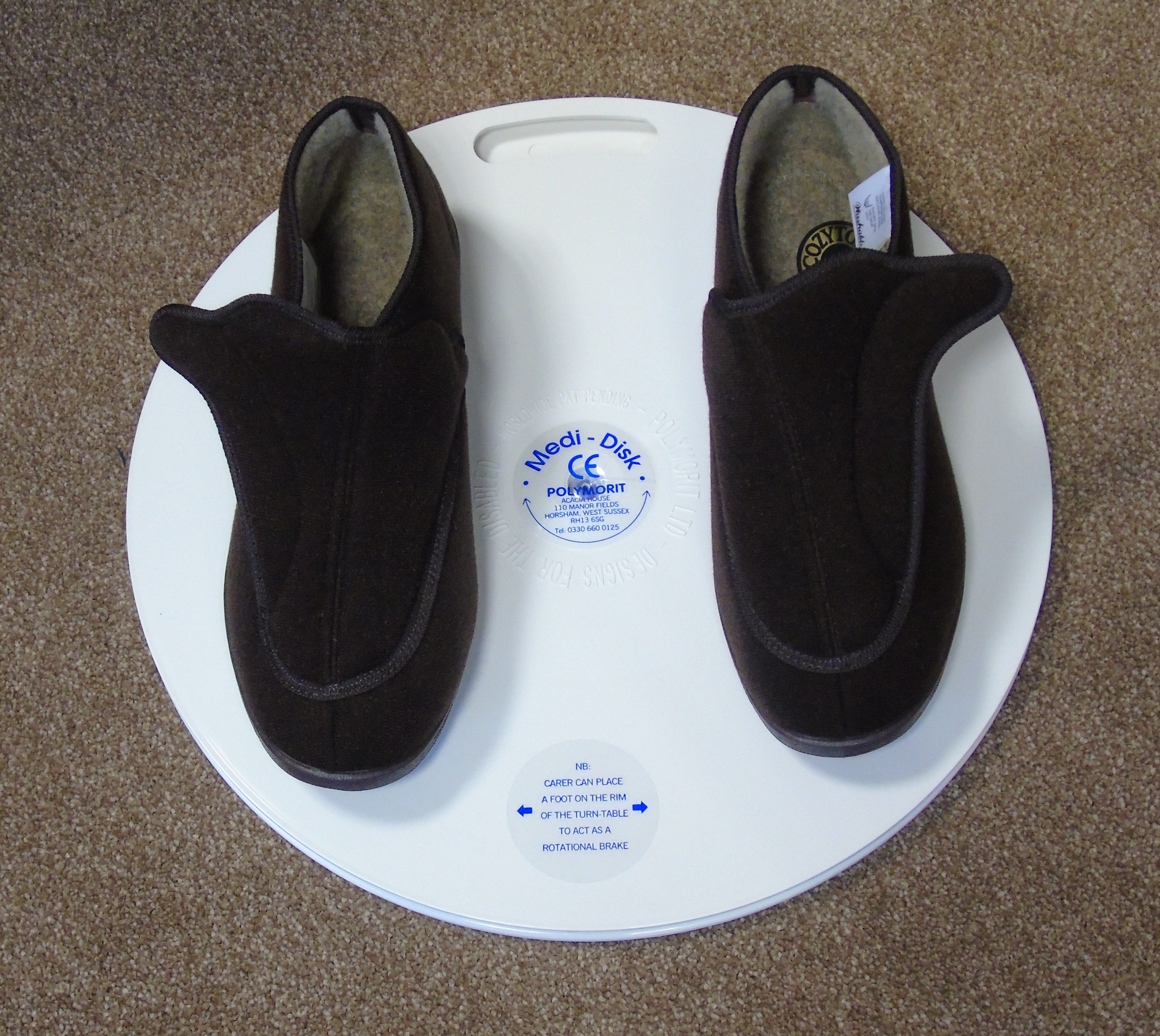 Pair of black slippers on a white circular medidisk with branding and certification logos.