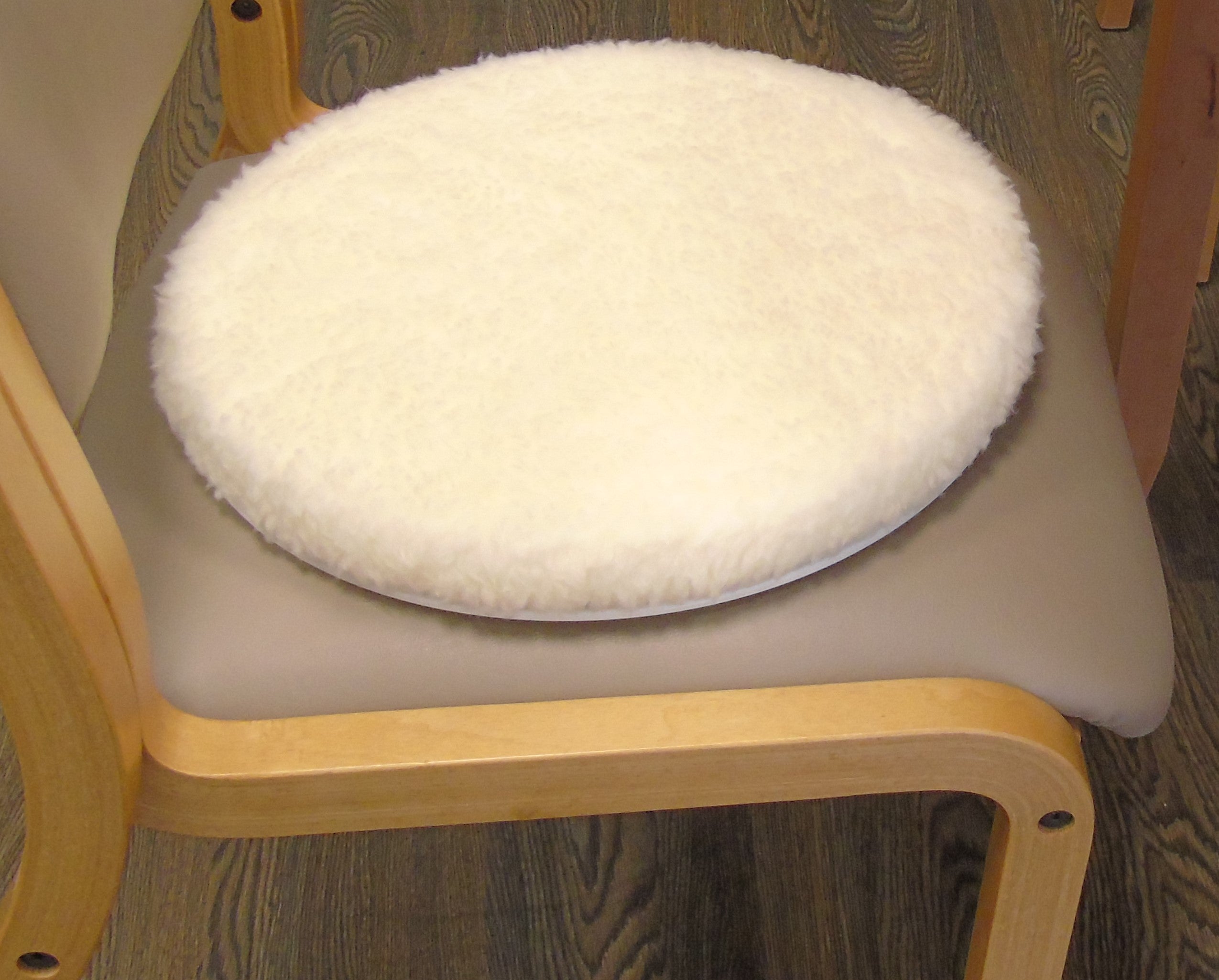 Round white turneasy turning disk cushion on a chair with wooden frame